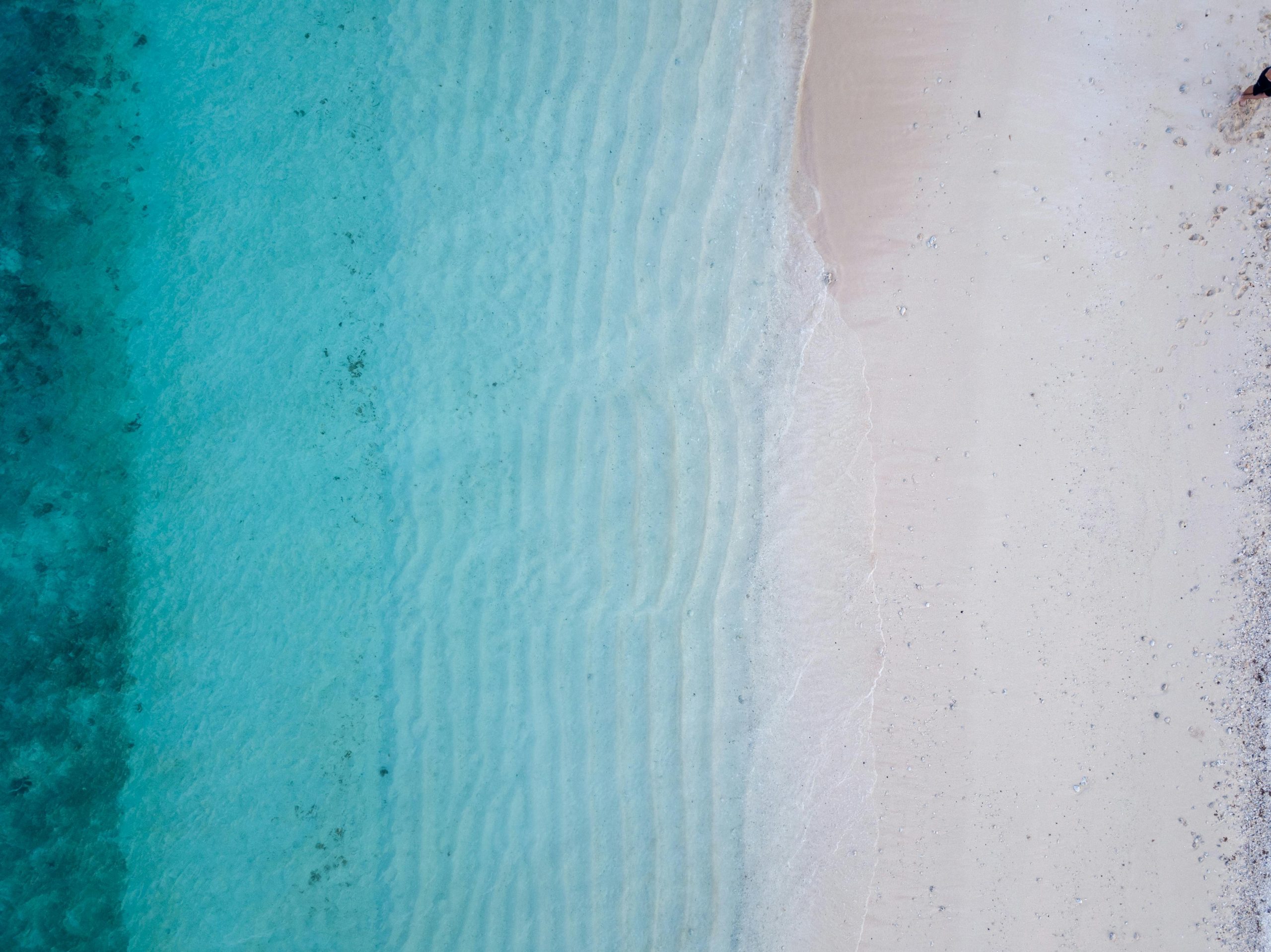 Aerial view of the beautiful turquoise ocean waves and pristine sandy beach in Fiji, perfect for a serene summer escape.